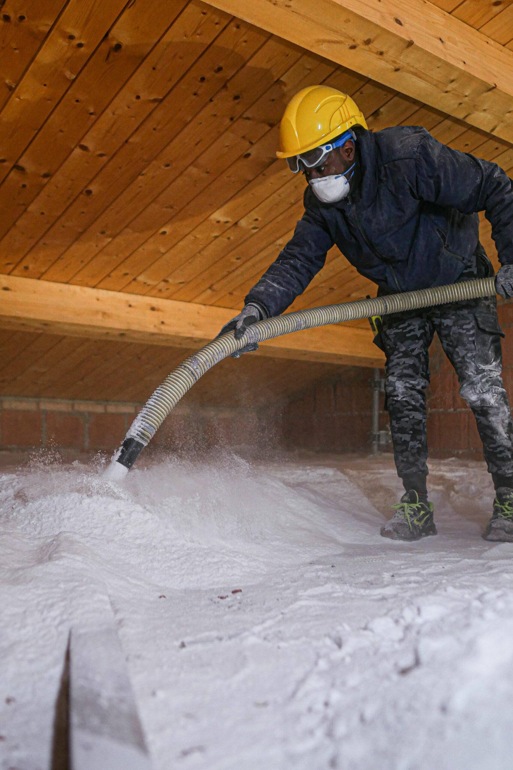 Operaio che applica isolante termico tramite insuflaggio in un sottotetto